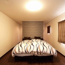 落ち着いた雰囲気の寝室。ベッドの背後に壁を設け、奥を物干し場に利用。
